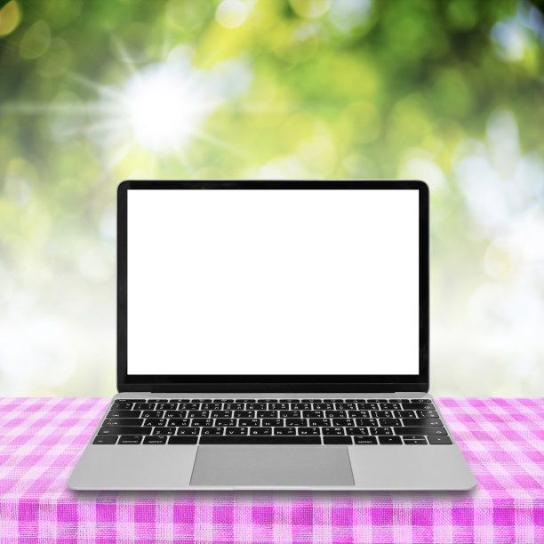 笔记本电脑与空白屏幕在桌子上与抽象的绿色背景。图片下载