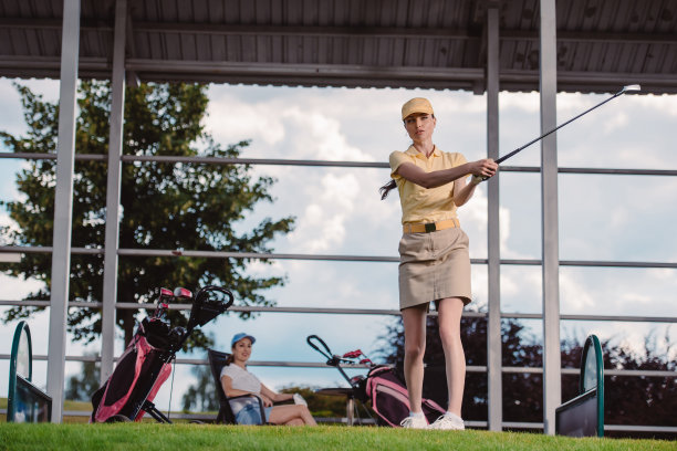 女性高尔夫球手在打高尔夫球时，朋友在高尔夫球场休息的选择性焦点图片下载
