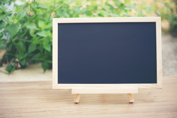 黑色板在木桌面与太阳和模糊的绿树虚掩背景，模板模拟展示的产品图片下载