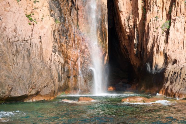 瀑布前面有一道红色的悬崖流入大海图片下载