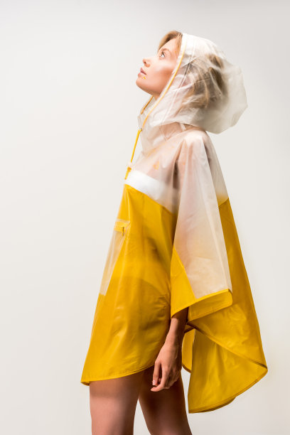 侧视图美丽的女人在雨衣看着孤立的白色图片下载