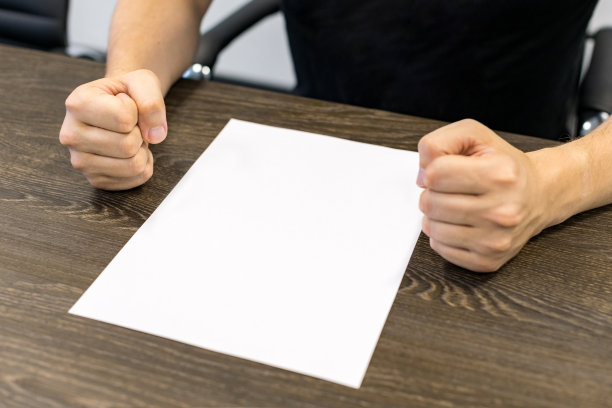 商人坐在桌边。桌子上有一张白纸。愤怒的手势。概念图。图片下载
