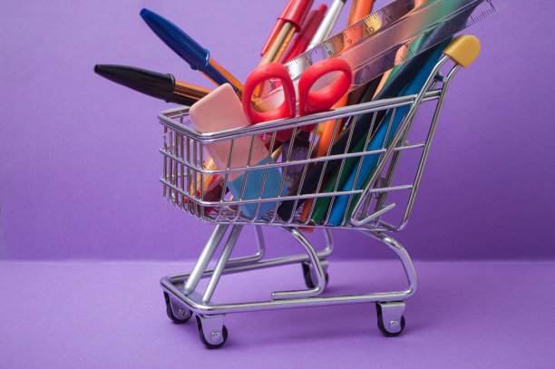 紫色背景的超市手推车里的学习用品图片下载
