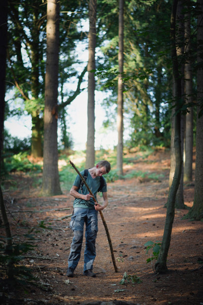 森林里的少年用刀砍树枝。图片下载