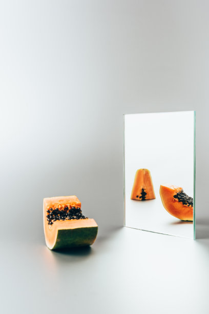 白色的桌子上，镜子里反射着木瓜图片下载