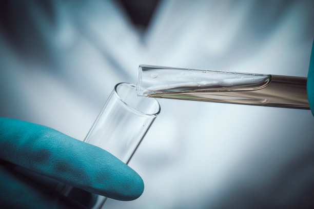 科学家将化学液体滴入有实验室玻璃器皿背景的烧瓶中，实验室研究概念，研究员将试剂滴入试管中。图片下载