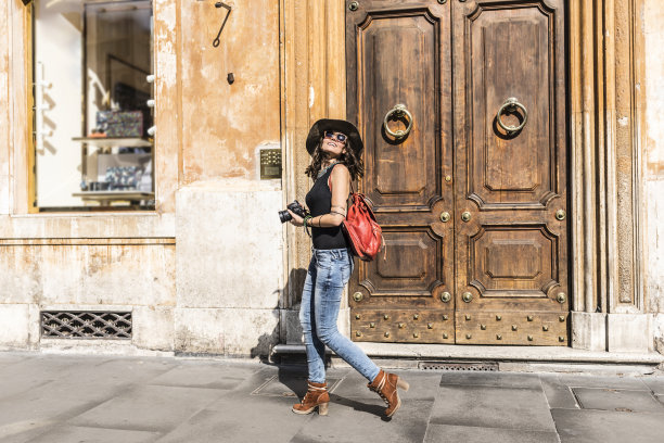 优雅的女人拿着相机走在街上图片下载