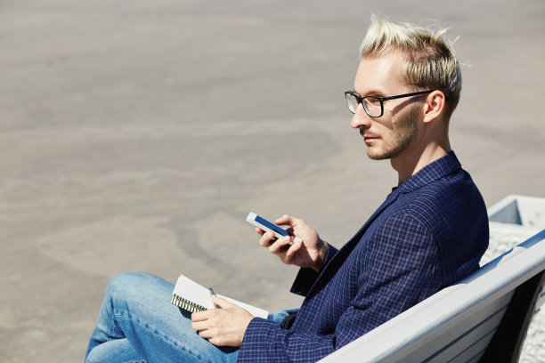 坐在长椅上拿着笔记本和智能手机的男人图片下载