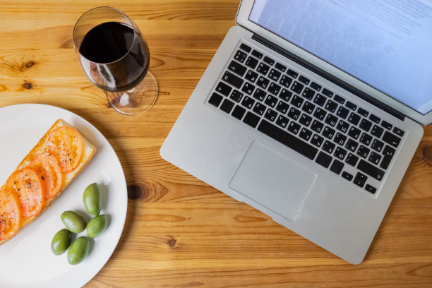 俯视图的笔记本电脑和傍晚的面包，橄榄和葡萄酒图片下载