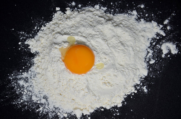 黑色背景上加面粉的鸡蛋图片下载