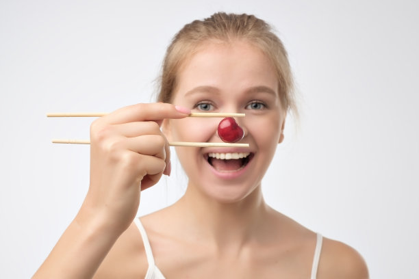 健康的年轻女子拿着一颗红樱桃图片下载