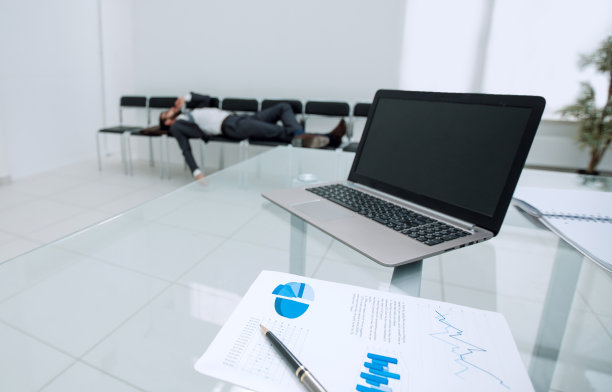 背景图片，一个笔记本电脑在一个空办公室的玻璃桌子上图片下载