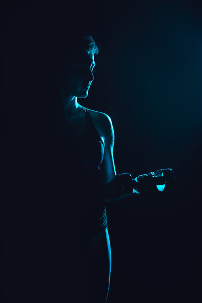 用哑铃锻炼的女运动员的色调图片，黑色背景图片下载