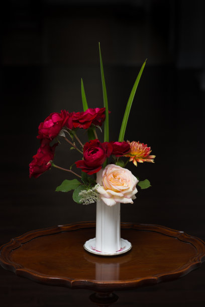 鲜切的玫瑰插在古董花瓶里，以深色为背景图片下载