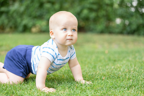 可爱的金发宝宝在草坪上爬行的肖像，沉思。体贴的孩子在思考。孩子心中的问题或想法概念图片下载