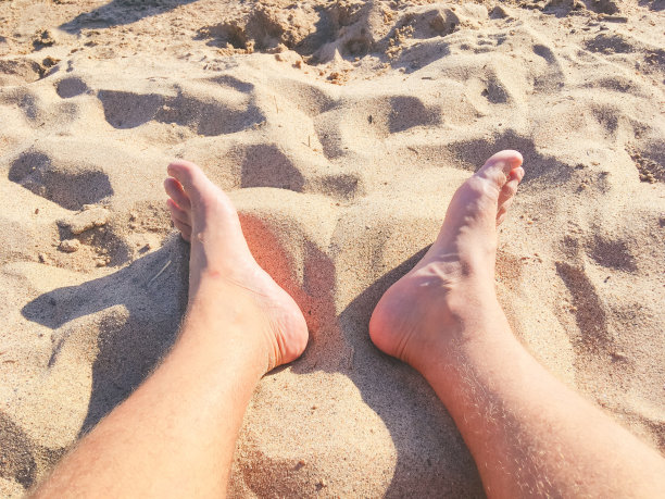 双脚踩在沙滩上。图片下载