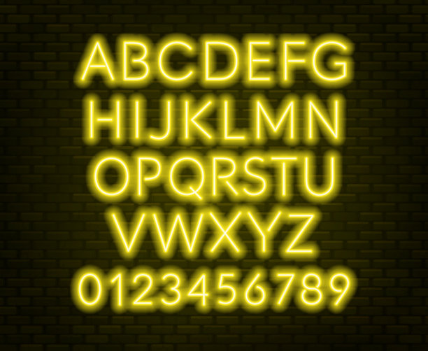 砖墙背景上的霓虹黄色字母。大写字母。图片下载