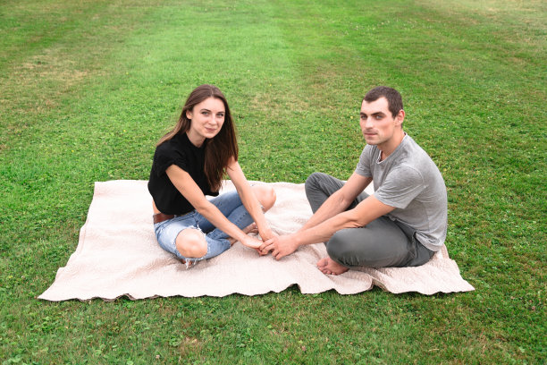 一对夫妇坐在草地上的毯子上图片下载