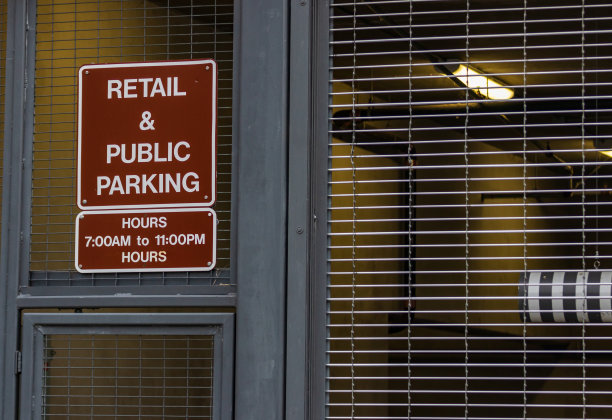 钢铁围栏旁的零售和公共停车场标志图片下载