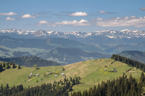 春光明媚的乡村风光。山上覆盖着森林和草地，雪山和蓝天白云。清晰环境的概念。自然背景图片下载