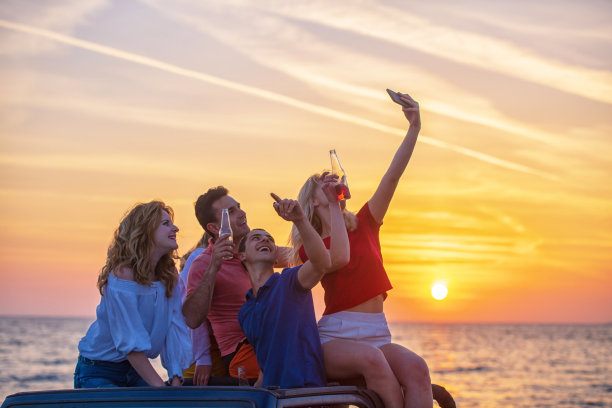 日落时分，五个年轻人在海滩上开敞篷车玩。图片下载