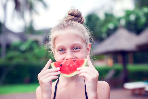 一个女孩在一个非常热的天吃一个冷的西瓜。概念照片的天气炎热，热浪，夏天的季节，孩子，享受生活，快乐，幸福，食物。图片下载