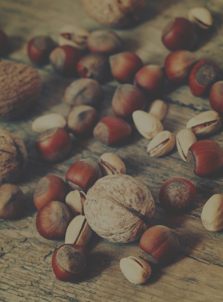木桌上放着核桃、榛子和开心果，有选择性的聚焦和有选择性的影像图片下载