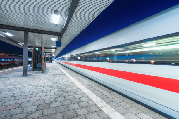 高速列车在火车站上运行，夜间有美丽的照明。移动模糊的现代城际列车在铁路站台上。旅客运输。铁路。旅行图片下载