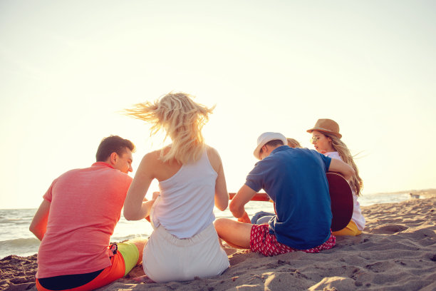 一群快乐的年轻人在美丽的夏日日落的海滩上跳舞图片下载