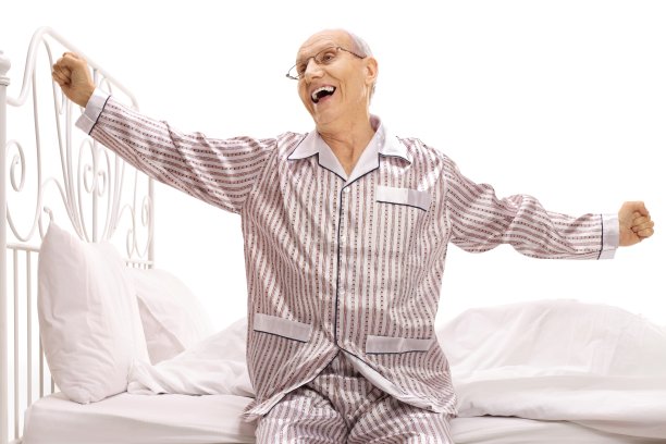 穿着睡衣的老人坐在床上伸懒腰图片下载