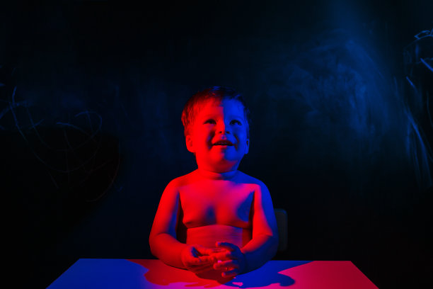 在黑暗的背景下寻找男婴。红蓝色调的照片与复制空间图片下载