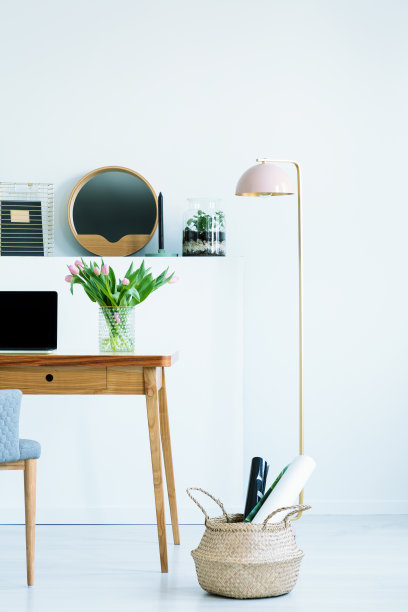 篮子和灯旁边的木桌，笔记本电脑和鲜花在工作空间内部。真实的照片图片下载