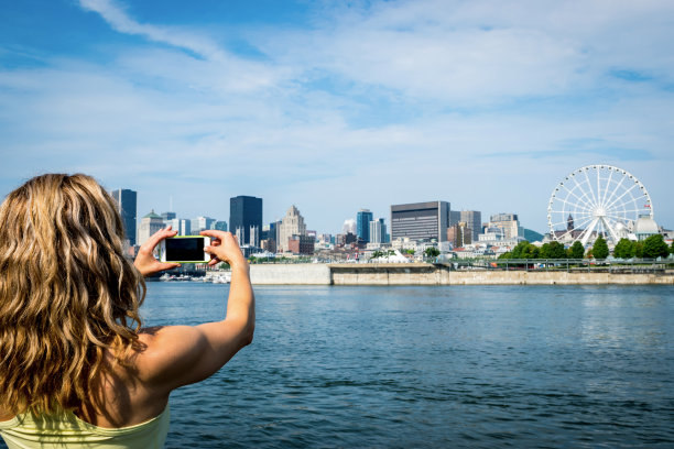 一个女人在河边拍城市的照片图片下载