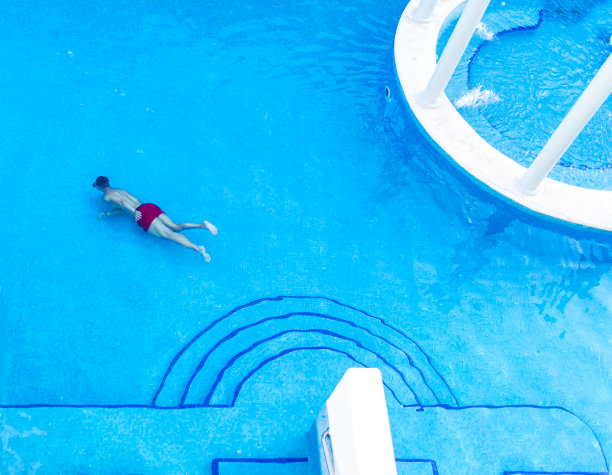 在一个豪华的蓝色瓷砖游泳池里，男人穿着浮潜器在水下游泳，在假期或度假时放松图片下载
