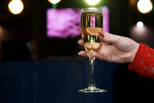 一个女人手里拿着一杯香槟，背景模糊不清。本空间图片下载