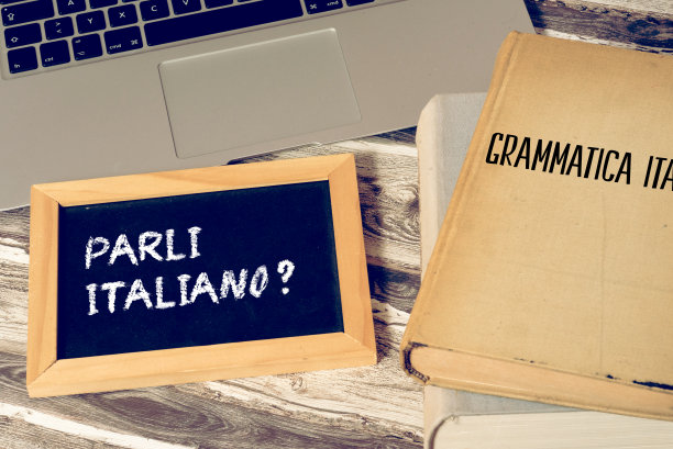 一台电脑，一本意大利语语法书和一块写着意大利语课文的黑板图片下载