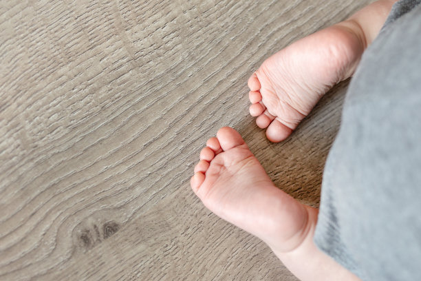 特写可爱的婴儿婴儿的脚在木地板的背景。有趣的可爱的高跟鞋。温柔的孩子的脚趾图片下载