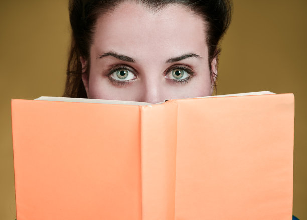 绿眼女人在打开的书上方看着摄像机图片下载