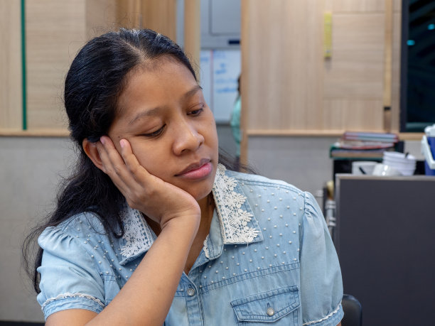 亚洲女性穿着夹克蓝色牛仔裤在餐厅里做一个无聊的脸后，等待了很长时间的约会对象。图片下载