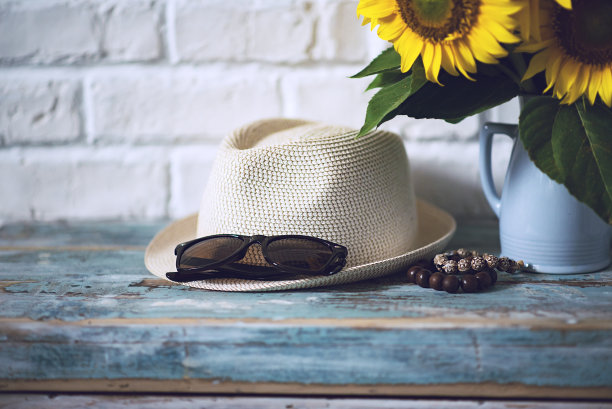 夏天的帽子和太阳镜，木手镯和一束向日葵在一个储物柜图片下载