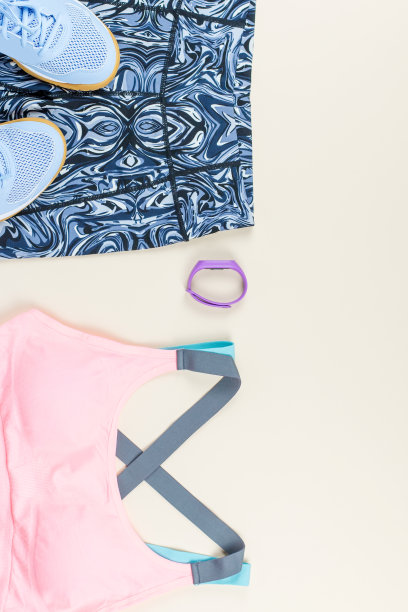 中性背景下的女性运动胸罩、紧身裤、运动鞋、耳机和健身追踪器。运动时尚的概念。图片下载