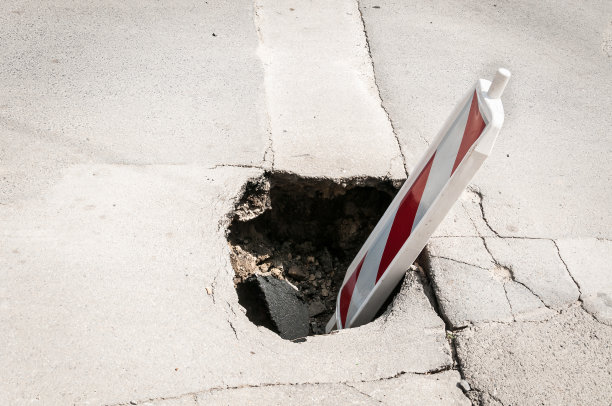 街道重建或建设路障，交通危险警告标志覆盖的开放洞的损坏和开裂的沥青在破碎的道路上作为预防关闭图片下载