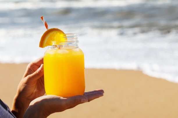 手里拿着果肉的橙汁，沙滩上有文字空间图片下载