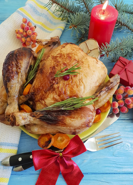 整只炸鸡，蓝色木质背景上的圣诞树树枝图片下载