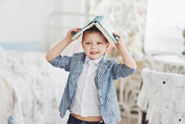 这张照片是一个勤奋的男孩，头上戴着一本书在做作业。这个男生对做家庭作业感到厌烦图片下载