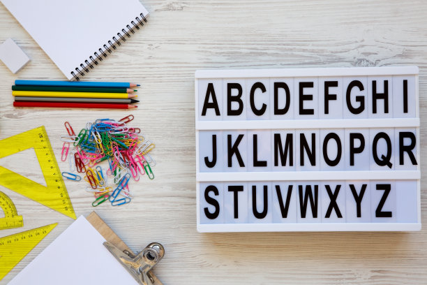 回到学校的概念。字母从A到z英语字母表现代板和配件的研究，在白色木制背景，俯视。从上面看，平躺着。图片下载