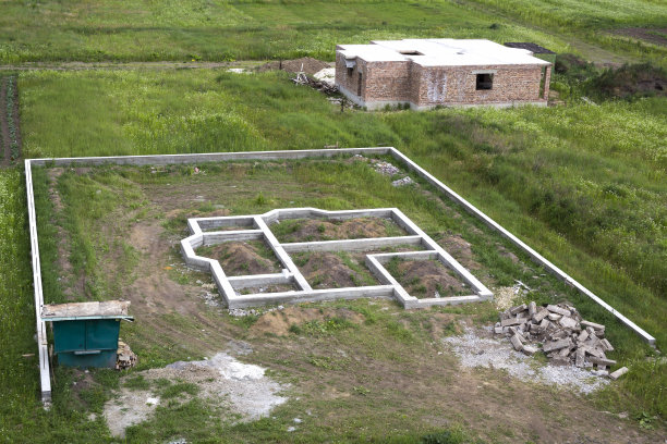 绿地里的建筑工地。在地面上挖沟，填满水泥作为未来房屋的地基和小木屋的砖地下室地板。建筑、建设和投资理念。图片下载