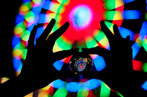 摩天轮穿过你手掌上的玻璃球。庆祝和休息的气氛。晚上冒险。明亮的颜色。手的轮廓图片下载