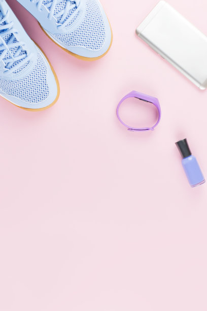 女式运动鞋，粉粉色背景上的健身追踪器。运动时尚的概念。平躺图片下载