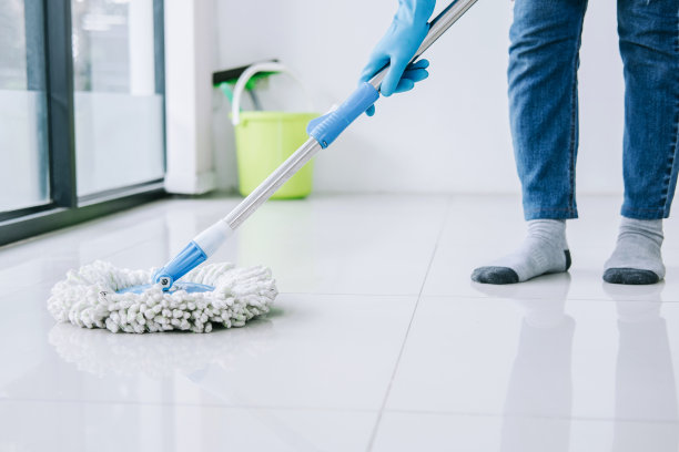 家政和清洁的概念，快乐的年轻女子在蓝色橡胶手套，用拖把擦拭灰尘，同时清洁地板在家里图片下载